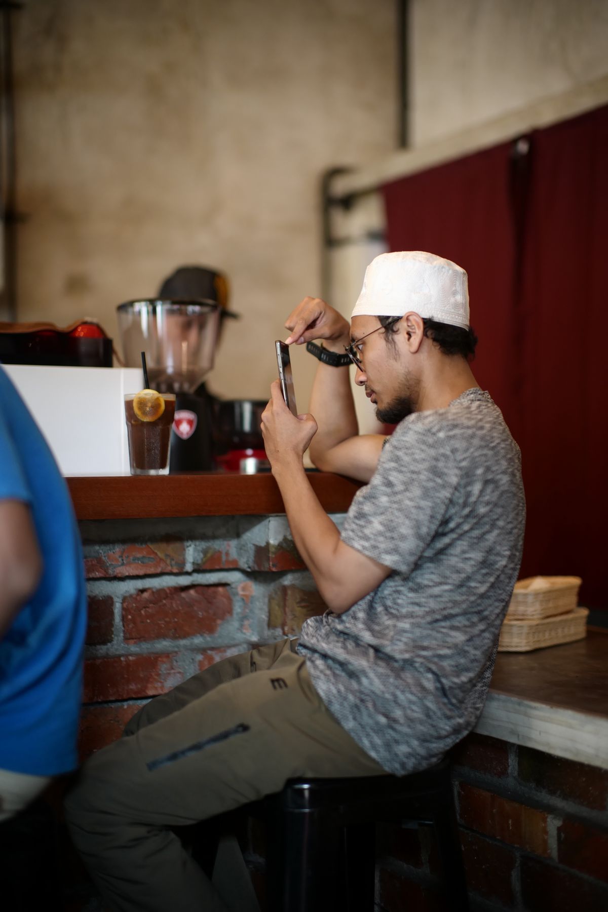 A man using a smartphone in a Malaysian cafe