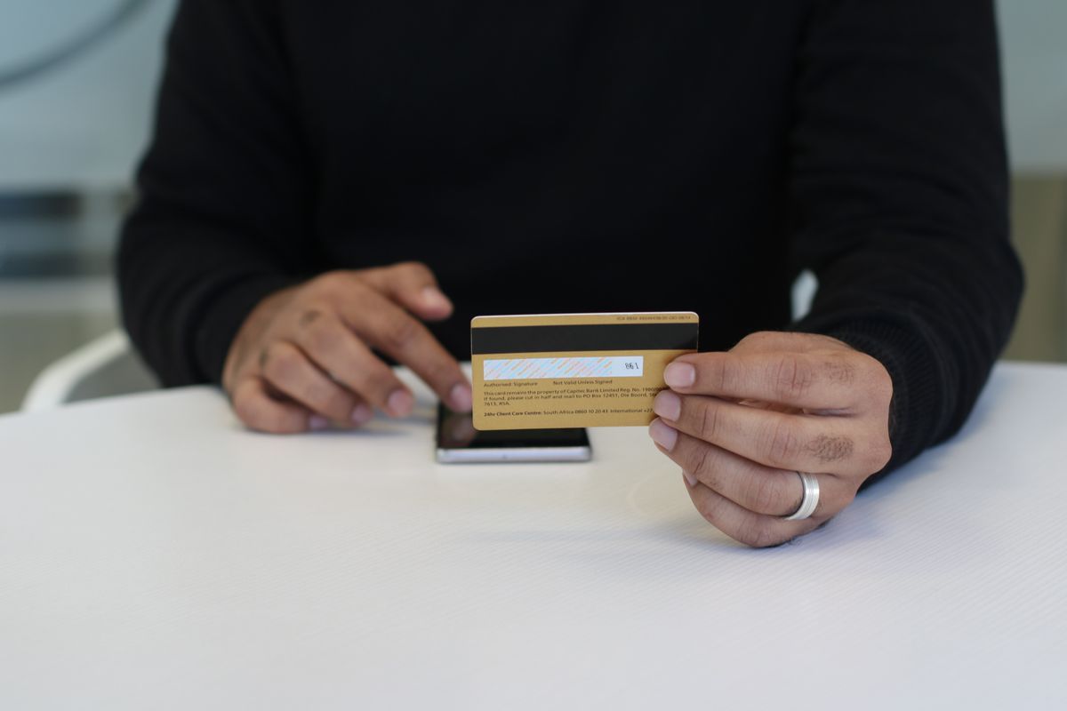 A person holding a bank card and smartphone