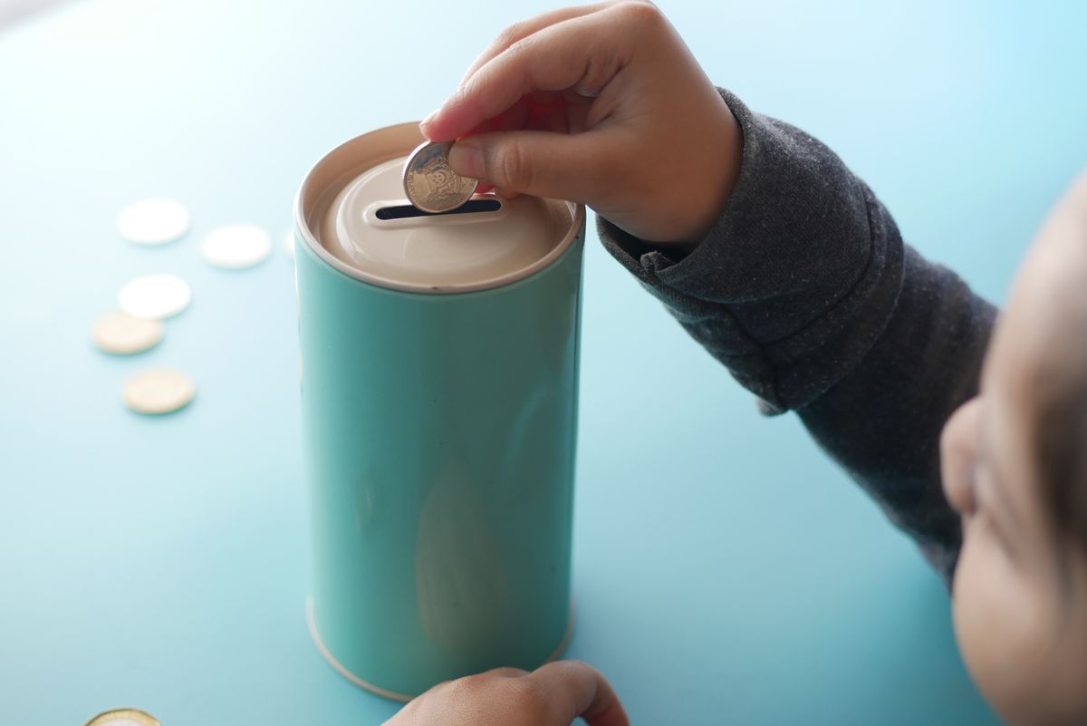 A child placing a coin into a savings container