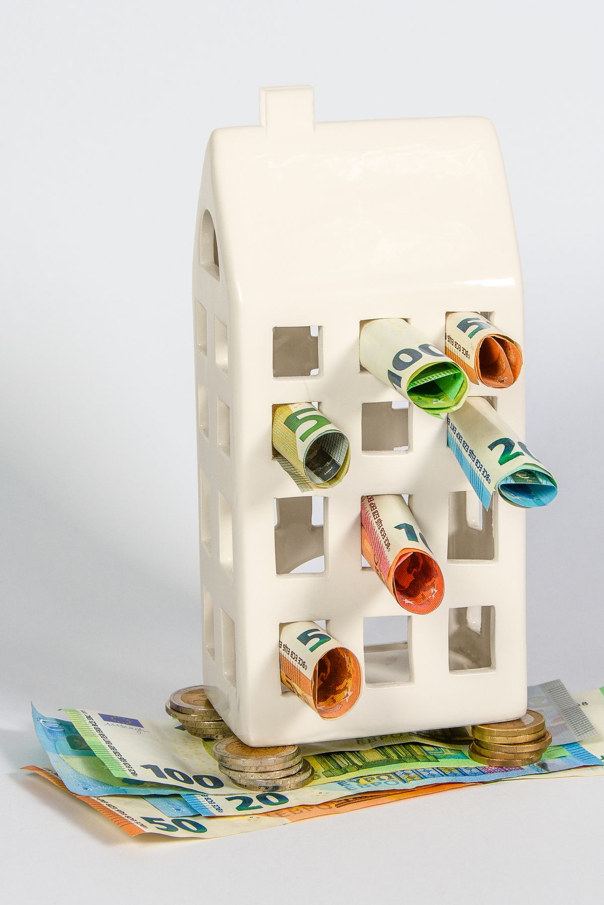 A small house-shaped savings bank with money and coins