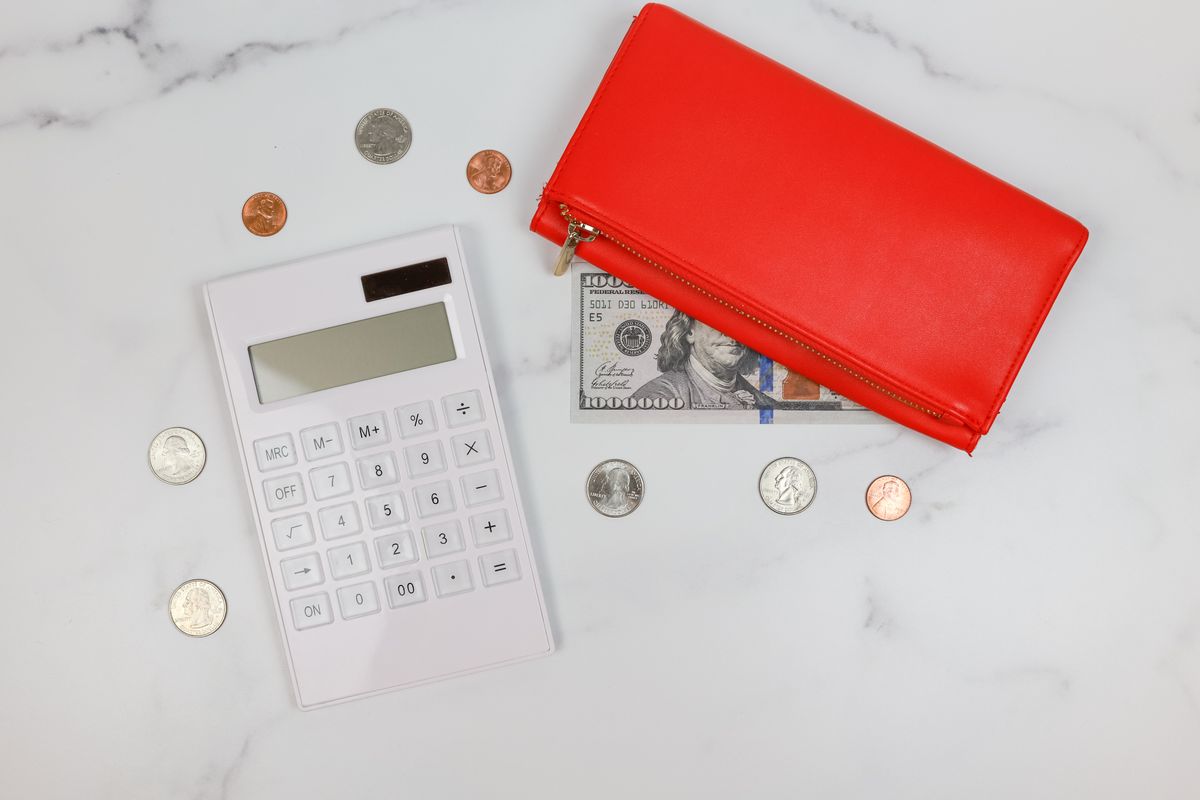A wallet, coins and calculator on a desk